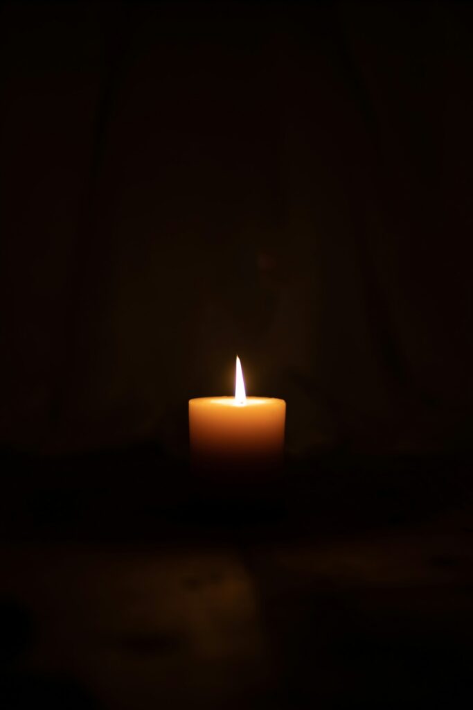 Single candle glowing in a dark room – hope in seasons of grief