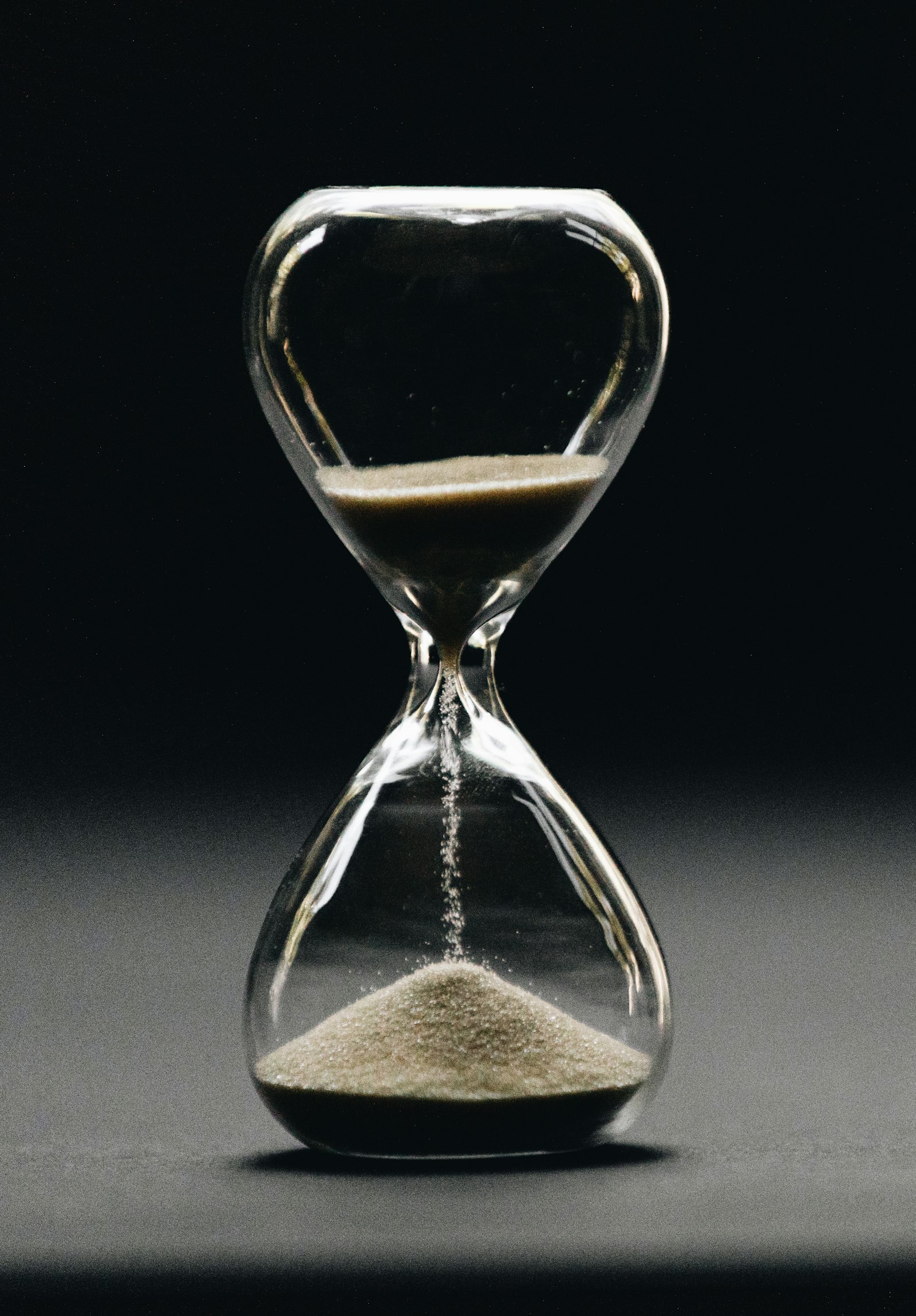 Clear hourglass with falling sand – time lost to compulsive habits
