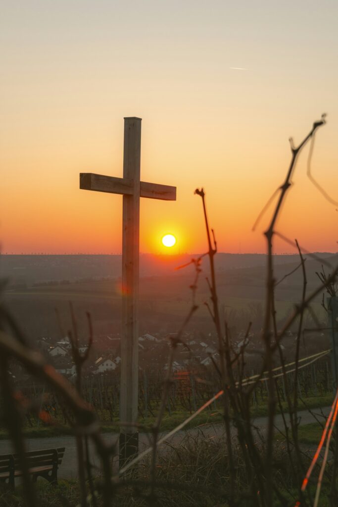 Wooden cross silhouetted against a vibrant sunset – spiritual growth